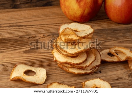 Dry apple slices stack on wood table. Dried apple chips, healthy fruit snack side view, dehydrated gourmet rings, crunch pitted sweet pear chips on rustic background