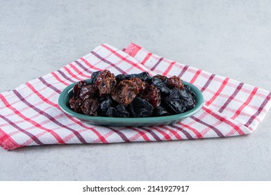 Dry black plums and dates in a blue platter, Ajwa dates. Dried date fruit of the ajwa type, Ajwa dates isolated in a plate on a white marble table, Madina Saudi Arabian dates, the most luxurious.