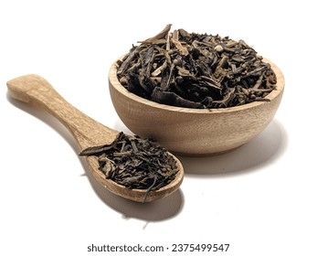Dry black tea leaves on wooden spoon wooden plate. Dried chinese tea leaves isolated on white background
