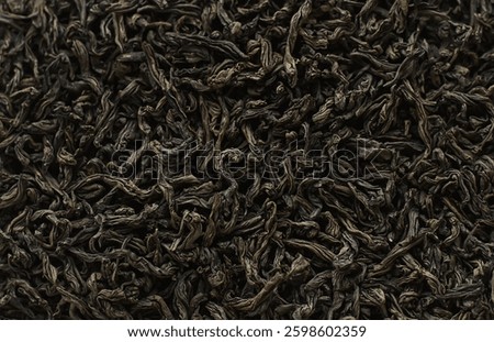 Dry black tea  pattern background. Dried black tea leaves background texture. Tea close-up. Top view from the top. Black long tea leaves. Ingredients for a hot drink.