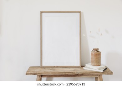 Dry bunny tail, lagurus grass bouquet. Ceramic vase on books. Old wooden bench, table. Blank vertical picture frame mockup. White wall background. Empty copy space. Scandinavian nterior. Autumn still - Shutterstock ID 2195595913