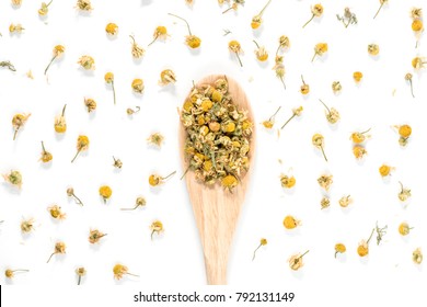 Dry Camomile Tea in a spoon on white background.