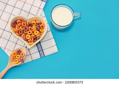 dry children's breakfast multicolored rings in a decorative plate and a glass mug with milk on a blue background - Powered by Shutterstock