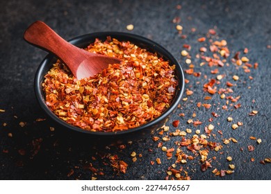 Dry chili pepper flakes. Crushed red peppers in bowl on the black table. - Powered by Shutterstock