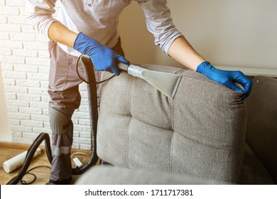 Dry Cleaner's Man Employee Removing Dirt From Furniture In Flat, Closeup, Vacuum Clean Sofa With Professional Equipment. Cleaning Service.