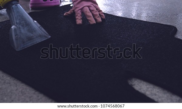 Dry cleaning of black mats\
for cars, vacuum cleaner removes dirt, pink rubber gloves, car\
washing.