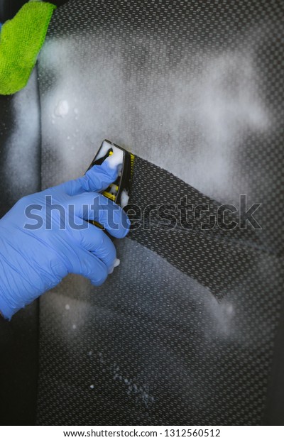 dry cleaning the car\
interior, close-up, the hand holding the brush and clean, using the\
foam, the seat