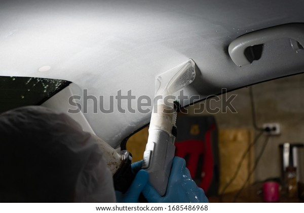 Dry cleaning of the car. Worker disinfects with a\
vacuum cleaner in a car.