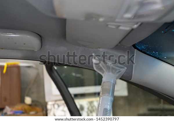 Dry cleaning salon cars. Worker uses washing vacuum
in the car.