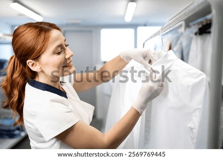 Dry cleaning worker preparing clean clothing for the customer.