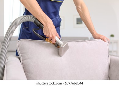 Dry cleaning worker removing dirt from armchair indoors