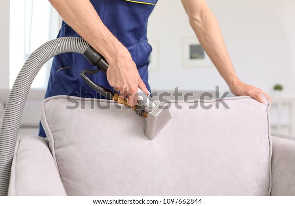 Dry\
cleaning worker removing dirt from armchair\
indoors