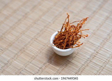 Dry Cordyceps Militaris Mycelium In White Bowl With Wooden Background. Orange Medical Mushroom For Good Health.