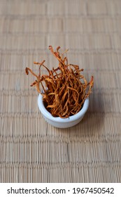 Dry Cordyceps Militaris Mycelium In White Bowl With Wooden Background. Orange Medical Mushroom For Good Health.