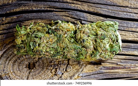 dry cut green cannabis hemp leaves ready to use for rest and pleasure. Macro detail of single cannabis bud (mangolope marijuana strain) over wooden dark background