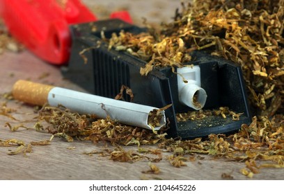 Dry Cut Tobacco Leaf, Cigarettes And Cigarette Machine On Wooden Table. Handmade Cigarettes