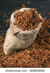 Dry Cut Tobacco Leaf On A Wooden Table. Tobacco In A Bag