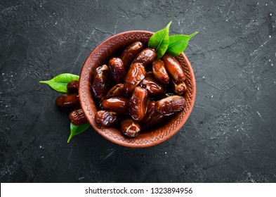 Dry date in a bowl on a black background. Dried fruit Top view. Free space for your text.