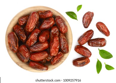 dry dates with green leaves in wooden bowl isolated on white background. Top view. Flat lay pattern