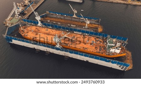 Dry dock with Cargo Ship maintenance or repair at floating dock in shipyard both deck crane loading during bring ship in to the dry dock.