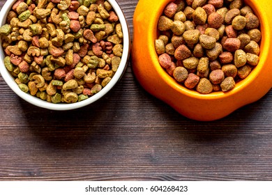 dry dog food in bowl on wooden background top view