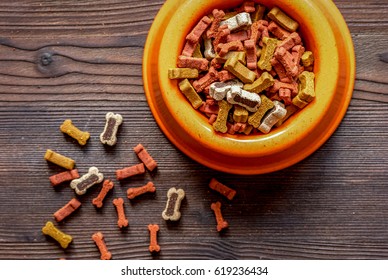 Dry Dog Food In Bowl On Wooden Background Top View