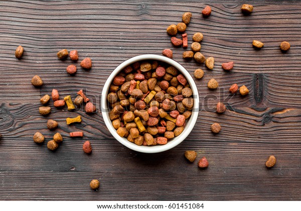 dry dog\
food in bowl on wooden background top\
view