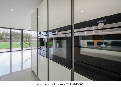 Dry Drayton, Cambridgeshire - Jan 10 2017: Contemporary Modern Kitchen Detail With Triple Ovens, Cabinets And Bifold Doors In Background