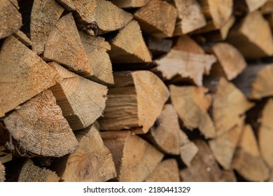 Dry Firewood Stacked In A Neat Woodpile. A Supply Of Wood For Kindling The Fireplace. Wooden Texture. The Concept Of Home Heating.