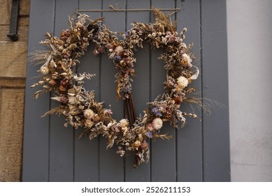 Dry flower heart shaped wreath hanging from a grey door. Decorative floral item. Vintage home decoration. - Powered by Shutterstock