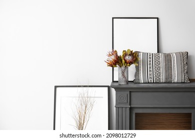 Dry Flowers In Vase, Pillow And Blank Picture Frames On Mantelpiece Near Wall