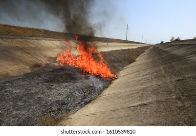 Dry Grass Burns In The Channel Of The Unused North Crimean Canal Near The Village Of Razdolnoye (Crimea, Crimean Peninsula).