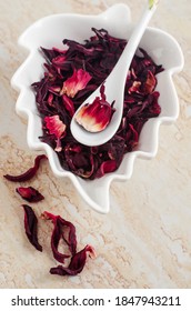 Dry Hibiscus Flowers In The White Porcelain Bowl, Selective Focus. Karkade For Preparing Herbal Tea. DIY Beauty Treatment And Spa.