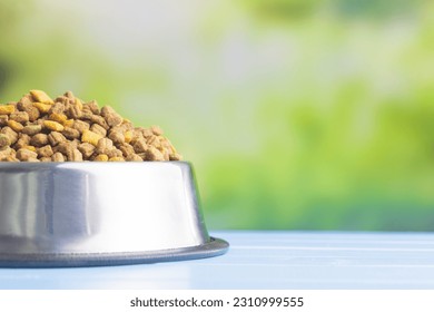 Dry kibble pet food in the bowl. Dog or cat food on garden table. - Shutterstock ID 2310999555