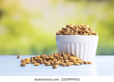 Dry kibble pet food in the bowl. Dog or cat food on garden table. - Shutterstock ID 2310999561