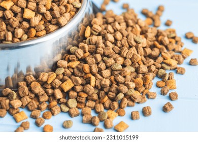 Dry kibble pet food. Dog or cat food on the blue table. - Shutterstock ID 2311015199