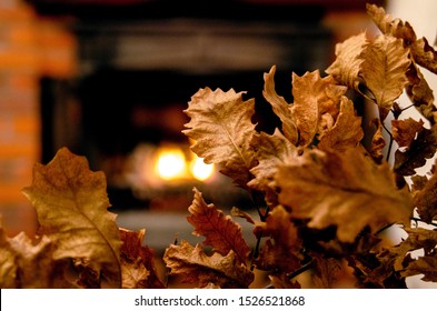 Dry leaves by the fireplace.Close up on orthodox Christmas symbol oak tree branch and candle light.Warm colors autumn and winter background