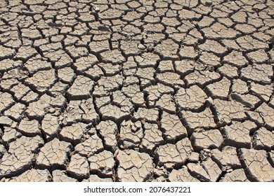 A dry, lifeless, barren clay land cracked in the African desert during global warming and climate change. A hot surface during drought is destroyed, eroded and textured. Copy space, background.