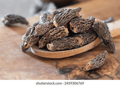 Dry Morel Mushrooms on Wooden Platter. Close-up of textured morel mushrooms, artfully arranged on a rustic wooden platter, emphasizing their unique structure. - Powered by Shutterstock