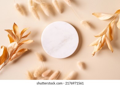 Dry natural grass, leaves and flowers frame with white marble podium, beauty and fashion concept mock up on beige background flat lay, top view, copy space - Shutterstock ID 2176971561