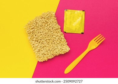 Dry noodles, a yellow fork and a bag of spices on a red and yellow background. - Powered by Shutterstock