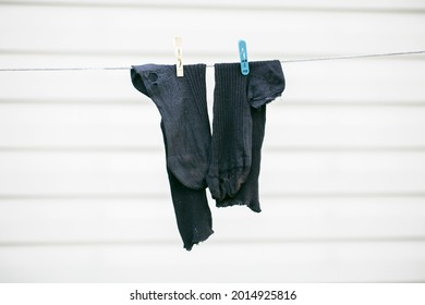 Dry old torn black socks on a rope. Poverty concept.