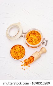 Dry Orange Lentils In Glass Jar. A Valuable Source Of Protein For A Healthy Vegan Diet. White Putty Background, Top View