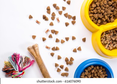 Dry Pet Food In Bowl And Toys For Dogs On White Background Top View