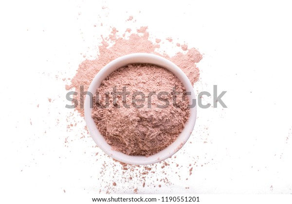Dry pink clay powder mask for face and body  in\
ceramic bowl isolated on\
white