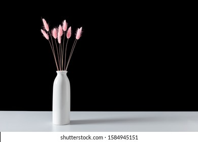 Dry Pink Grass In Vase On White Shelf On Black Wall Background. Floral Home Decor. Interior Flowers