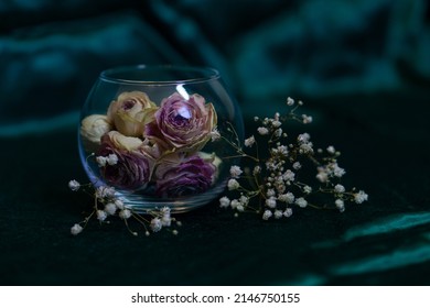 Dry Pink Roses In A Round Glass Vase On An Emerald Background