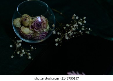 Dry Pink Roses In A Round Glass Vase On An Emerald Background