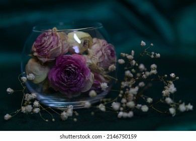 Dry Pink Roses In A Round Glass Vase On An Emerald Background