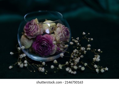 Dry Pink Roses In A Round Glass Vase On An Emerald Background